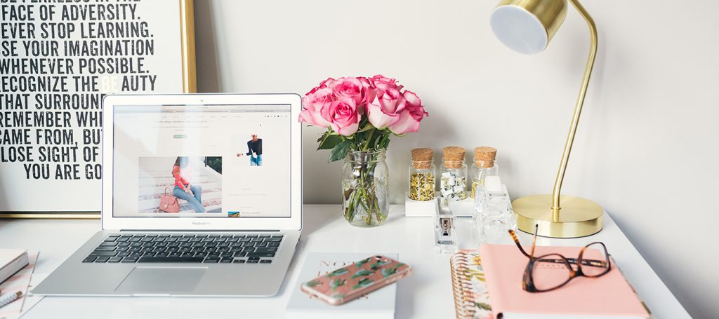 white table with laptop, lamp, and flowers - importance of blogs on websites