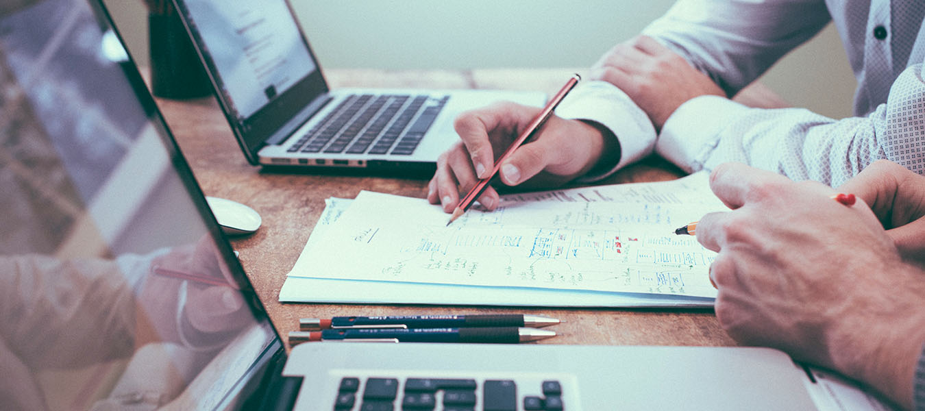 helloquence-5fNmWej4tAA-unsplash men at desk with paper, pencil, laptops - running a sales promotion for supplements
